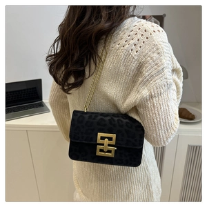 Detail of a leopard print crossbody bag with gold chain strap worn over a beige sweater