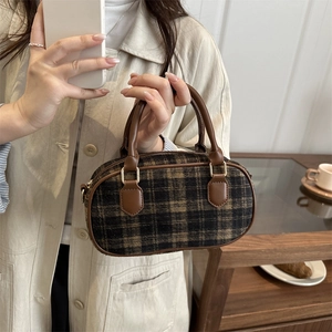 Classic brown plaid mini handbag with leather handles held by a model in a cafe setting