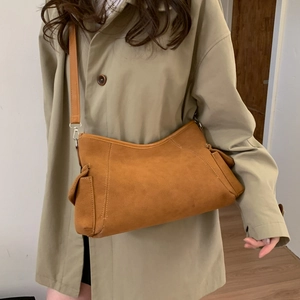 Minimalistische bruine suède schoudertas met vintage klepzakken getoond op model