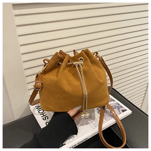 Detail of brown suede bucket bag with drawstring closure and golden pearl chain