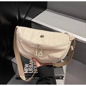 Detail view of a beige nylon crescent bag featuring dual zippers on urban books
