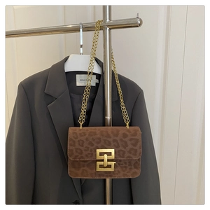 Detail view of a vintage leopard print square bag with a gold buckle on a suit jacket