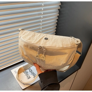 Detail of beige nylon crescent bag with triangle zipper pull and round emblem