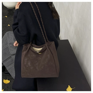 Detail of dark brown tote bag featuring unique woven shoulder straps and soft suede texture