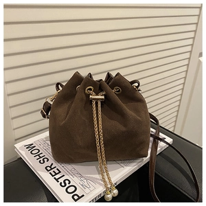Detail of dark brown suede bucket bag with gold chain and large pearl drawstring charms