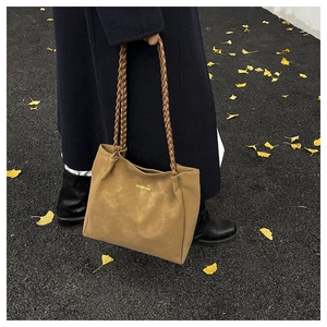 Detail of vintage tote bag with woven handles on autumn ginkgo leaf background