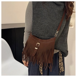 Detail of dark brown suede crossbody bag featuring long fringes and golden metal buckle