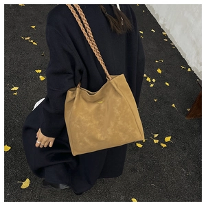 Close-up of a brown suede tote bag featuring unique braided rope handles and golden logo