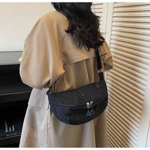 Detail of black nylon crescent bag featuring metal hardware and adjustable shoulder strap