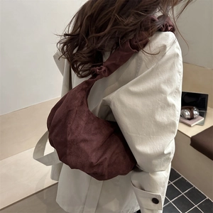 Sac à main plissé en velours côtelé marron foncé porté par un mannequin, style minimaliste