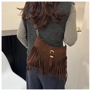 Rear view of a model wearing a brown suede tote bag with long tassels and metallic hardware