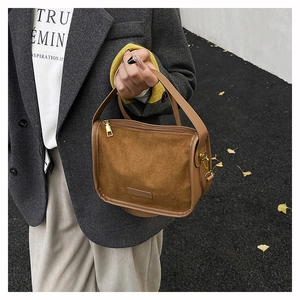 Gros plan d'un sac à bandoulière en daim marron avec anneaux métalliques dorés fins