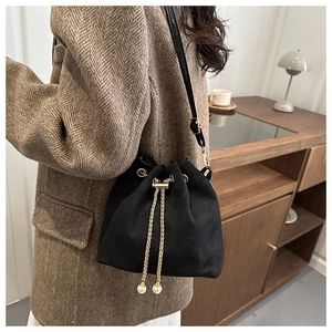 Detail of black frosted bucket bag with elegant pearl drawstring and golden chain