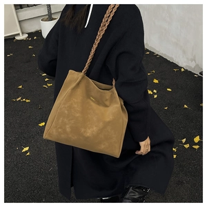 Brown tote bag with braided handle detail shown on model in autumn street scene