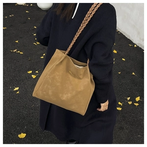 Detail view of khaki brown matte tote with twisted braided strap and gold brand logo