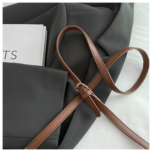 Detail of brown litchi leather strap with adjustable gold buckle on blazer background