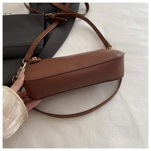 Detail of brown cylindrical grained leather crossbody bag with gold metal hardware