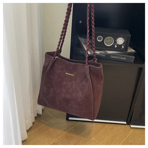 Close-up of vintage burgundy suede tote bag featuring braided handles and front logo