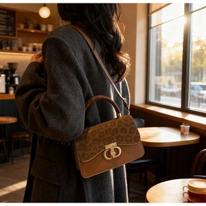 Detail of leopard print patchwork shoulder bag with golden T-shaped lock on grey coat