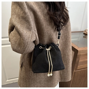 Close-up of black bucket bag featuring golden chain drawstring and elegant pearl charms