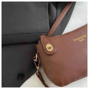 Detail of brown litchi pattern leather bag with golden twist lock and logo