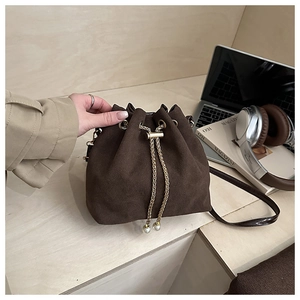 Detail of dark brown suede bucket bag with gold chain drawstring and pearl accents