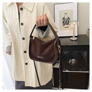 Close-up of vintage brown suede shoulder bag with gold hardware and removable strap