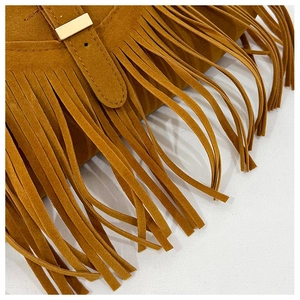Close-up of brown suede tassel details and gold metal square buckle on bohemian tote bag