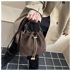 Detail of dark brown suede bucket bag featuring gold chain drawstring and pearl charms