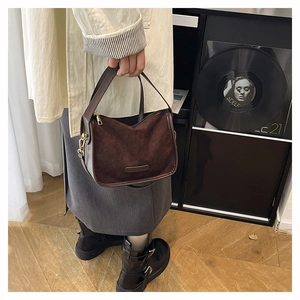 Détail d'un sac à main en daim marron avec garnitures dorées et coutures en cuir