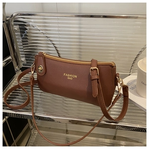 Detail of caramel pebbled leather crossbody bag with gold fashion lettering and hardware