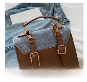 Detail of golden metal hooks and brown leather handle on a denim patchwork handbag
