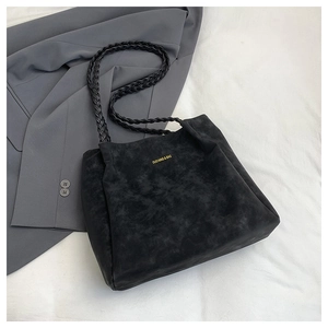 Detailansicht der schwarzen Wildledertasche mit geflochtenem Gurt und Goldlogo