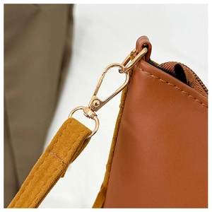 Detail of light gold lobster clasp and yellow suede strap on brown leather tote bag