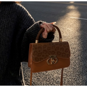 Detail of leopard print crossbody bag with gold CD metal clasp and textured leather