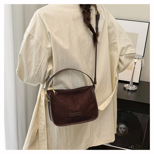 Detail of vintage brown frosted suede shoulder bag shown with a white trench coat