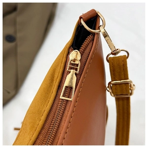 Detailed macro view of light gold metal zippers and stitching on a tan tote bag