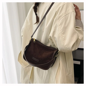 Détail d'un sac bandoulière en daim marron foncé avec des finitions dorées chic
