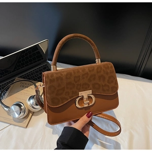 Detail of leopard print flap and gold circular buckle on a brown leather handbag