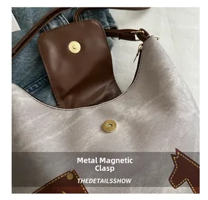Dettaglio della chiusura magnetica sulla borsa tote argento con ricamo a cavallo