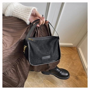 Détail du sac noir montrant la texture en daim mat et les finitions en cuir lisse