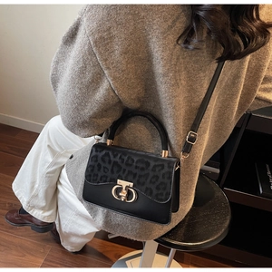 Detail of elegant black handbag with leopard print flap and golden ring hardware