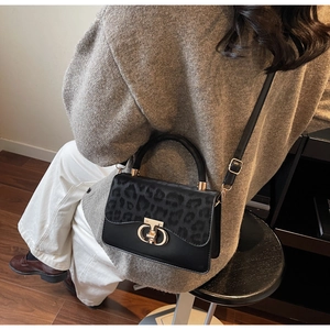 Detail of the chic leopard print flap and golden ring lock on the black leather handbag