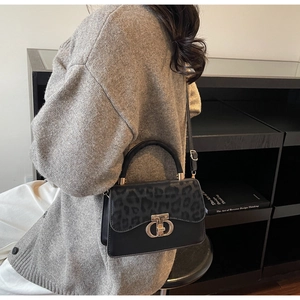Detailed view of leopard print panel and golden circular metal lock on black handbag