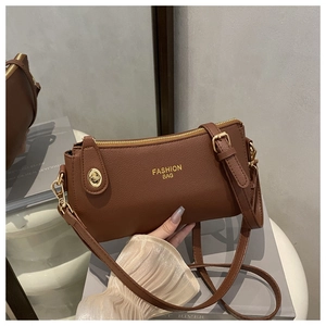 Detail of a brown leather crossbody bag with FASHION BAG logo and gold metal buckle