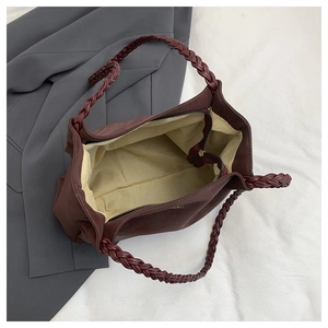 Close-up of burgundy tote bag with woven handles and interior zippered pocket detail