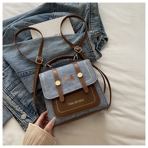 Detail of vintage denim crossbody bag featuring cat illustration and dual buckle straps