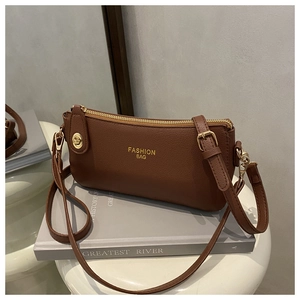 Close-up of brown litchi leather bag with gold hardware and logo on decorative books