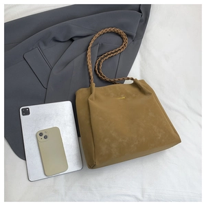 Detail of khaki minimalist tote bag with woven handle and embossed gold lettering on leather