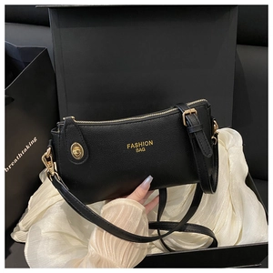 Detail of black lychee grain leather handbag with gold metal hardware and FASHION logo